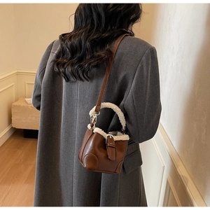 Mini sac seau marron avec bordure en simili mouton porté par un mannequin en blazer