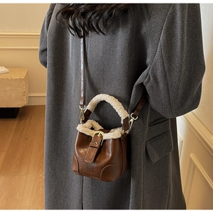 Détail d'un sac seau en cuir marron avec bordure en fausse fourrure blanche et boucle dorée