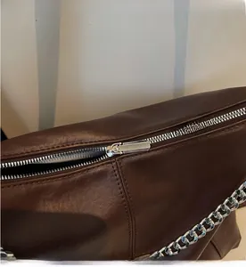 Detail of dark brown leather bag showing smooth silver zipper and chunky chain decor