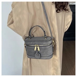 Detail of grey bucket bag with white contrast stitching and gold zipper closure