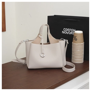 Close-up of cream textured leather bucket bag with silver charm on wooden background