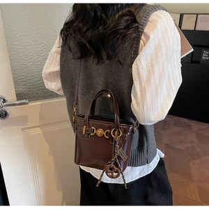 Detail of vintage brown leather handbag with gold heart buckle and knotted charm