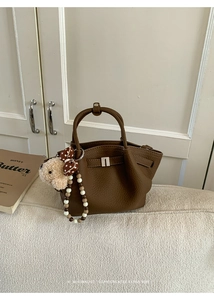 Detail of coffee brown lychee pattern bucket bag with plush bear charm and beaded handle