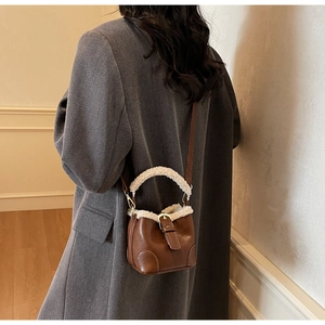 Détail du sac seau marron foncé avec bordure en peau de mouton sur manteau gris