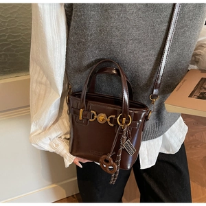 Close-up of retro brown bucket bag with heart metal buckle and abacus charm detail