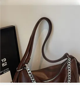 Detailed macro view of dark brown leather bag with chunky silver chain and strap