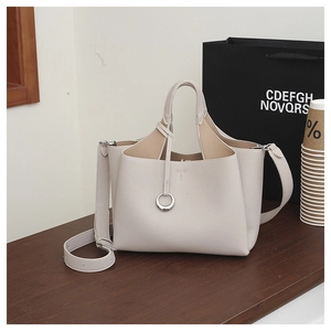 Close-up of beige lychee texture leather bucket bag with silver metal ring and strap