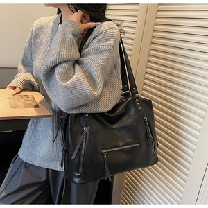 Detailed view of black retro tote bag featuring functional zippers and metallic rivets