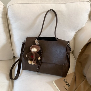 Dettaglio della borsa tote vintage in pelle marrone con ciondolo a forma di orsetto