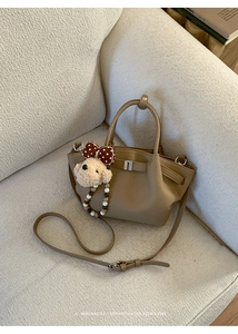 Close-up of khaki retro bucket bag with plush puppy charm and beaded chain detail