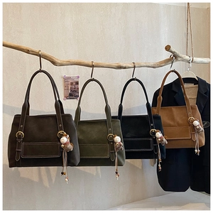 Quatre sacs cabas vintage en daim de différentes couleurs suspendus à une branche
