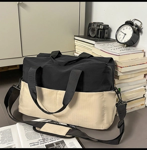 Dettaglio dei manici rinforzati e della tracolla imbottita sulla borsa da viaggio bicolore