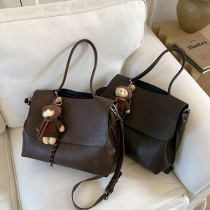 Dettaglio di borse tote premium in marrone scuro e cioccolato con ciondoli a forma di orso