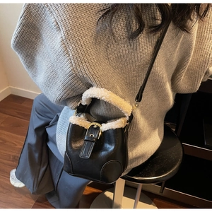 Détail du sac seau en similicuir noir avec bordure en laine blanche et boucle dorée