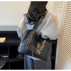 Black large capacity shoulder bag with tassel zippers shown on a model's back