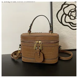 Detail of a brown leather bucket bag with crocodile texture and white contrast stitching