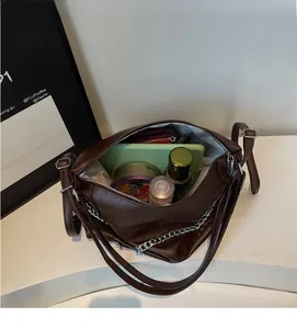 Detail view of large capacity interior for brown shoulder bag with silver chain