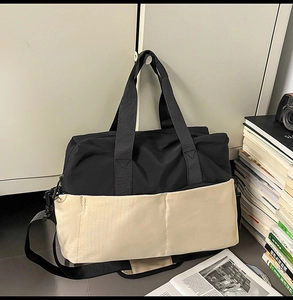 Dettaglio della borsa da viaggio bicolore con cinghie rinforzate e tasche anteriori