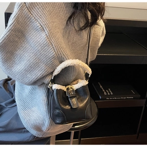 Détail du sac seau en similicuir noir avec bordure en fausse fourrure et boucle dorée