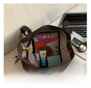 Intérieur spacieux d'un cabas marron foncé avec doublure rayée contenant une tablette
