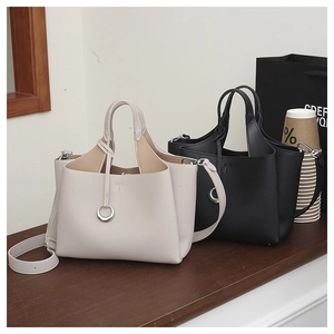 Detail of lychee pattern leather tote bags with metal ring accents and strap