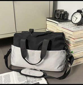 Dettaglio della borsa da viaggio bicolore con tracolla regolabile su una scrivania