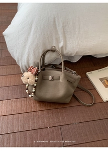 Detailed texture of brown pebble leather bucket bag with cute plush bear charm