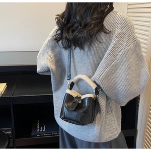 Détail du sac seau vintage en cuir noir avec bordure en peau lainée et boucles dorées