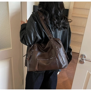 Rear view of a model wearing a large vintage brown tote bag with multiple zip pockets