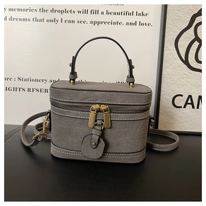 Detail of grey crocodile embossed bucket bag with gold zippers and leather handle
