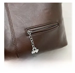Détail de fermeture éclair sur sac cabas marron foncé avec pendentif trèfle cœur