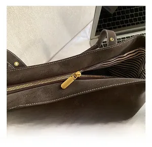 Détail de la fermeture éclair dorée sur un sac cabas marron avec doublure rayée