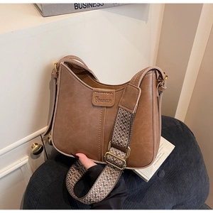 Close-up of vintage brown shoulder bag featuring an ethnic style woven wide strap