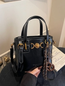 Classic black bucket handbag with gold heart accent and designer pretzel pendant accessory