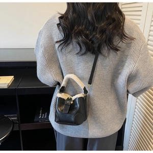 Détail du sac seau bicolore avec bordure en peluche porté par un mannequin