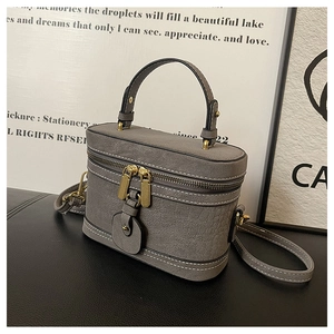 Detail of grey mini box bag with lychee texture leather and gold zipper closure