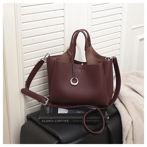 Close-up of burgundy lychee leather texture and metal ring detail on a bucket bag