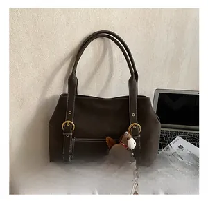 Détail d'un sac cabas en daim marron avec coutures contrastées et pendentif poney
