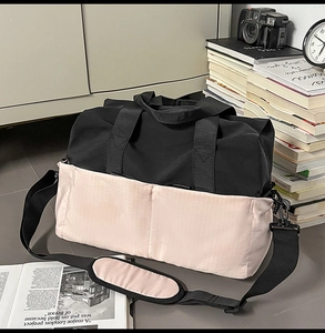 Dettaglio borsa da viaggio nera e rosa con tracolla accanto a libri vintage
