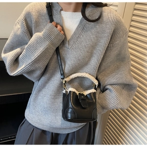 Détail d'un sac seau en cuir noir avec bordure en peluche blanche et dorures