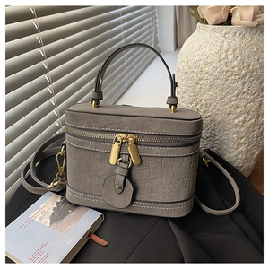 Detail of grey crocodile pattern vanity bag with white stitching and gold hardware