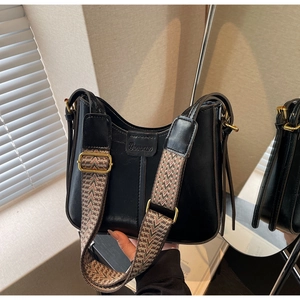 Detail of black vintage shoulder bag with textured geometric wide strap and gold hardware