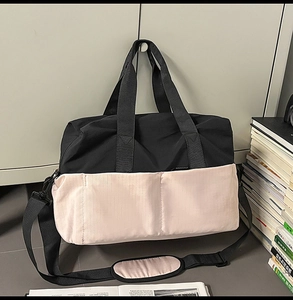 Dettaglio borsa da viaggio bicolore con trama in nylon e tracolla regolabile imbottita