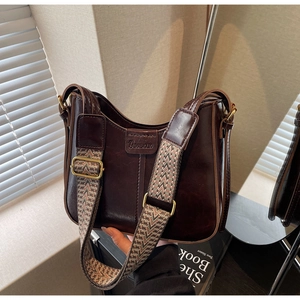 Detail of dark brown leather bucket bag with jacquard strap and brand embossing