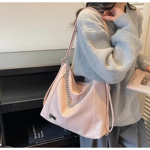 Detail of pink faux leather tote bag with silver chain and litchi grain texture