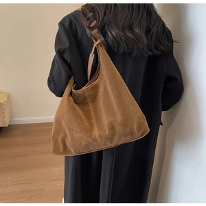 Detailed side view showing vertical stitching on brown suede shoulder tote bag