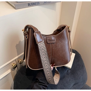 Detail of vintage dark brown bucket bag with wide jacquard strap and gold hardware