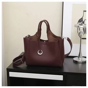 Detail of dark wine red bucket bag with litchi grain leather and silver ring decor
