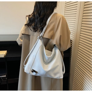 Detail of white leather tote bag featuring a silver chain strap and heart metal charm