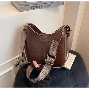 Detail of dark brown vintage crescent bag featuring wide geometric woven shoulder strap
